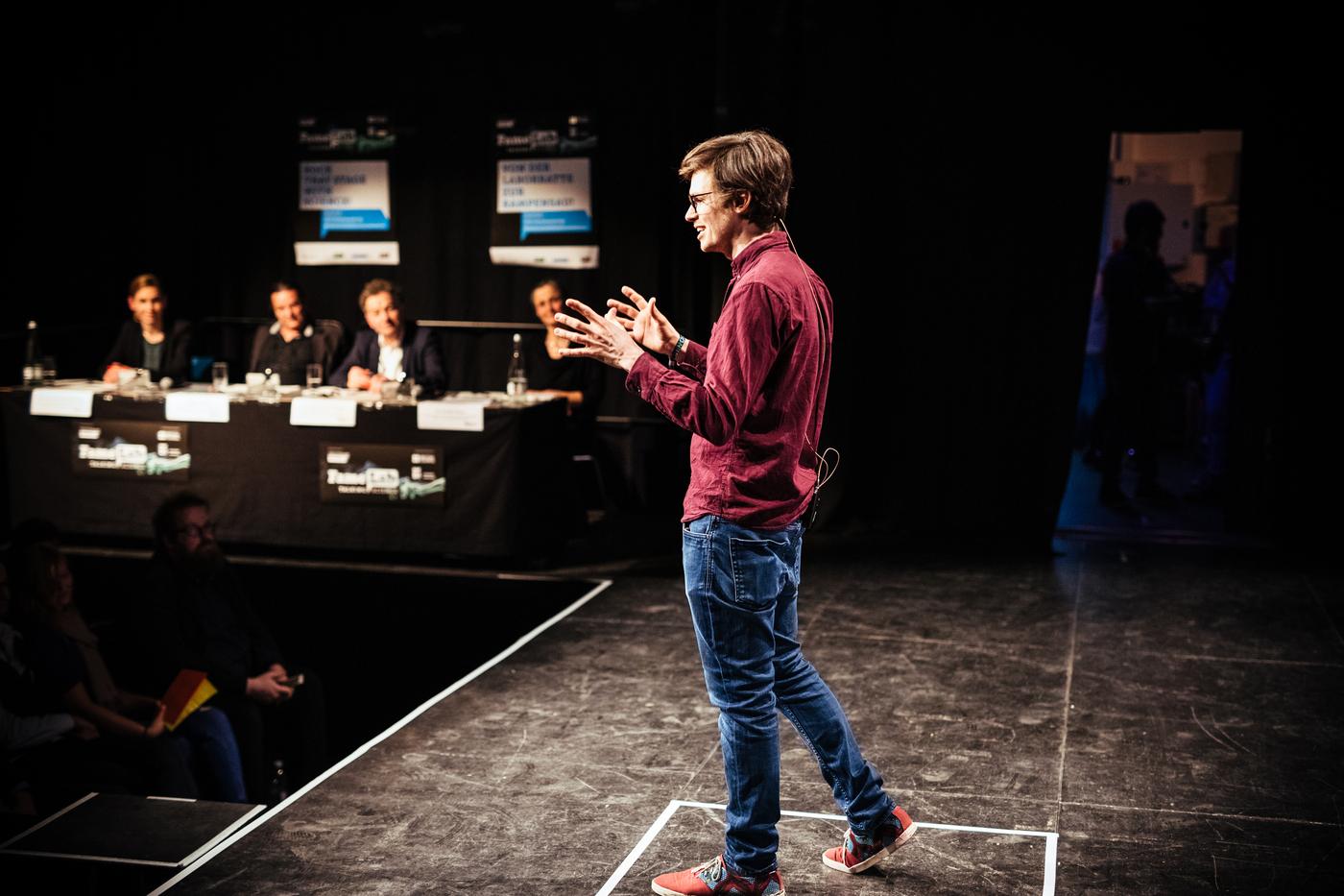 André speaking on stage at FameLab Karlsruhe